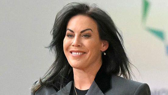 Jennifer Carroll MacNeill is seen arriving at the European Union–Gulf Cooperation Council (GCC) summit in Brussels on October 16, 2024.
She has long black hair and is smiling. She is wearing a grey suit with black trim, a black T-shirt, and a silver necklace.

