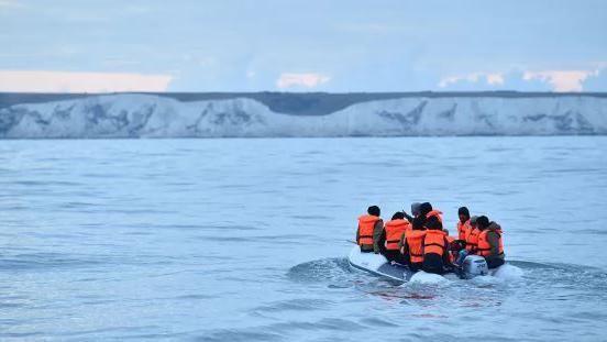 People with life jackets on a dinghy headed towards Dover