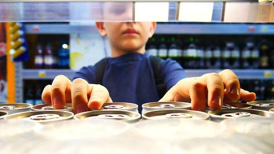 Child taking cans off supermarket shelf