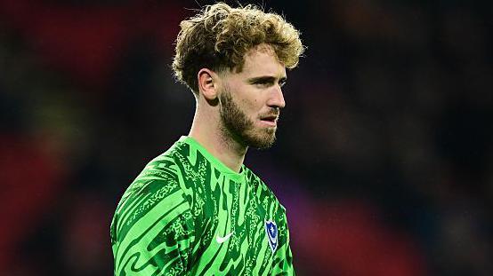 Nicolas Schmid looks on at a game for Portsmouth while wearing his green club shirt 
