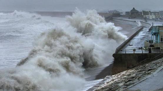 Chesil Cove in Portland during stormy weather in winter 2015. Large crashing waves are battering the shoreline and sea walls.