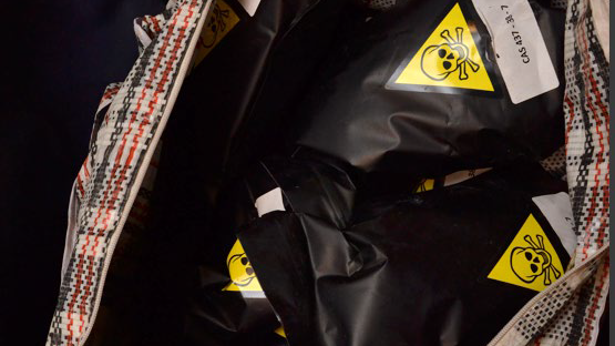 Black packages bearing yellow skull-and-crossbones triangles in a red-white- and blue holdall