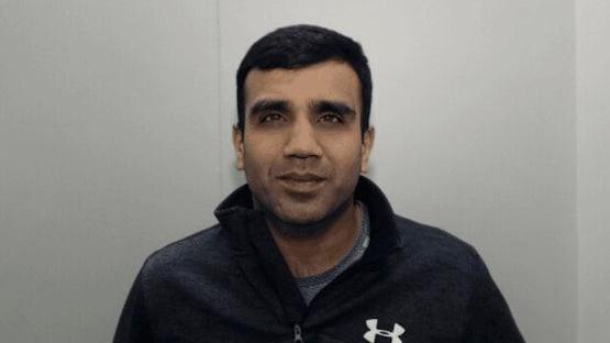 A police mugshot of Omar Din who is smirking at the camera