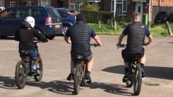 Three men on bikes in a street 