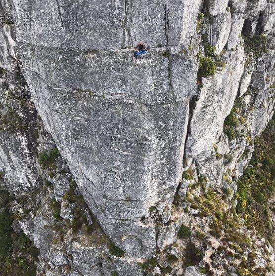 A rescue worker tries to help a person trapped on a narrow ledge