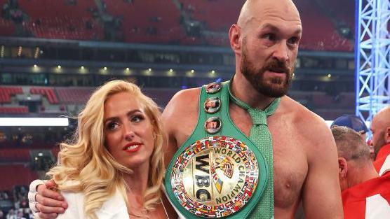 Tyson Fury with his arm around Paris Fury and the WBC heavyweight championship belt over his shoulder