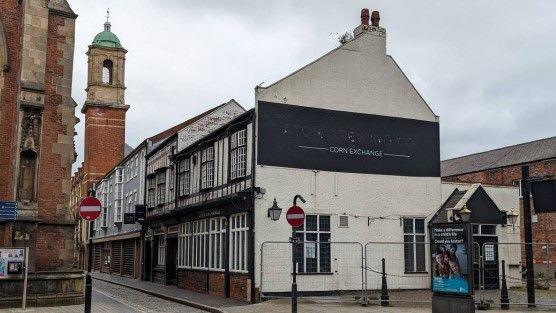 The front of the Corn Exchange pub, it is screened off using metal fencing and the signage has been taken down.