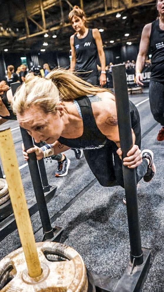 Leigh pushes a heavy sled while her race partner walks behind her ready to take over.