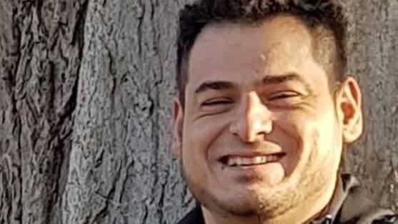 Alberto Ursu: he has short dark hair and wears a black jacket. He is pictured smilng and standing in front of a tree. 