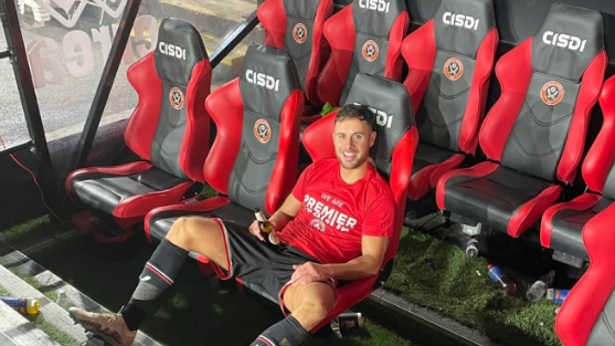 George Baldock sits in the dugout after Sheffield United secured promotion back to the Premier League