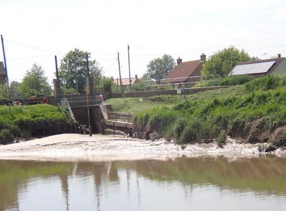 The River Great Ouse at Salters Lode in Norfolk, showing silt levels above the water line at the river bank and the entrance to the lock, which goes under a road bridge.