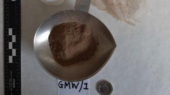 A silver bowl with brown powder - possibly drugs 