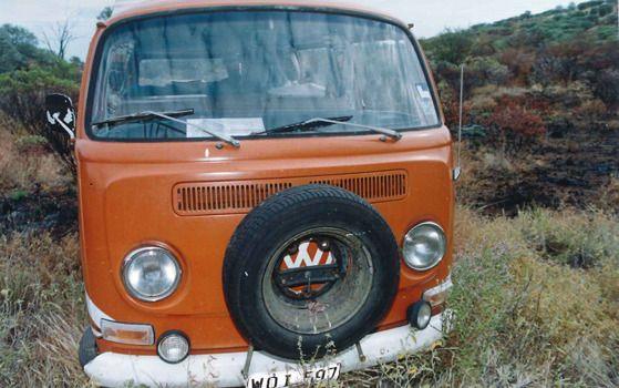The front of an orange VW Kombi van pictured in bushland 