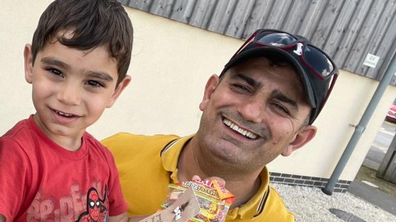 Muhammad Esmael in a Spiderman t shirt is held by his smiling father