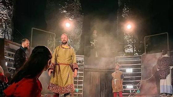 A number of actors on stage during a performance of Henry I in the ruins of Reading Abbey