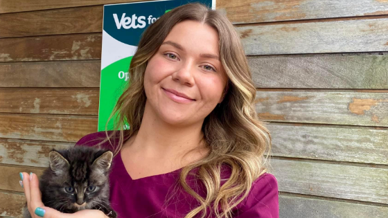 Sammie Roberts is looking at the camera while holding a tabby kitten. Ms Roberts has long brown hair. She is wearing a pink coloured top.