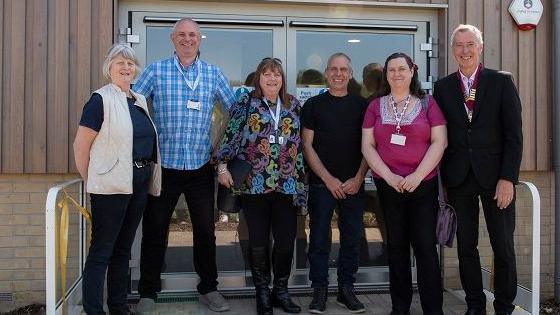 A group of people - with Lesley Scott-Boutell at the centre - outside a building