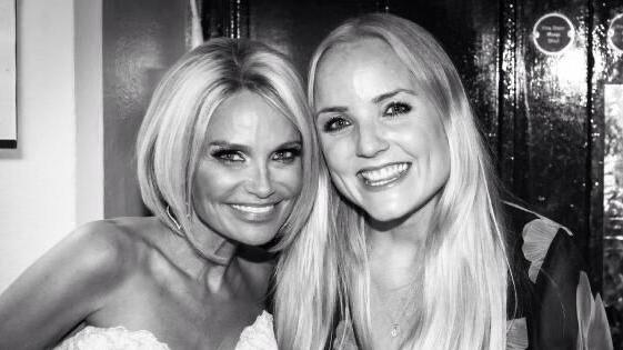 A black and white image of Kerry Ellis standing next to Kristin Chenoweth. Kerry has long blonde hair and wears a floral blouse while Kristin has a short blonde bob and wears a strapless white blouse.