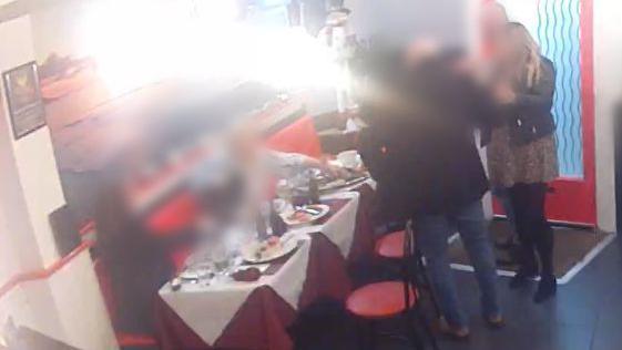 A still taken from CCTV footage in Tinels Seafood and Grill. The faces of the diners have been blurred out. The group is around a table covered in red and white cloths and surrounded by red chairs. Bottles of wine and plates of food are in front of them.