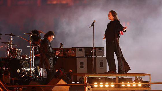 Ozzy Osbourne of Black Sabbath performs during the Birmingham 2022 Commonwealth Games Closing Ceremony at Alexander Stadium on 8 August 2022. Tony Iommi is with him, to one side, playing the guitar.