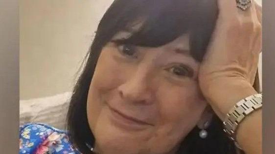 Karen O'Leary, a middle-aged lady with dark hair and a watch on her left wrist. She is smiling at the camera.