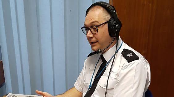 A seated police officer wearing a headset