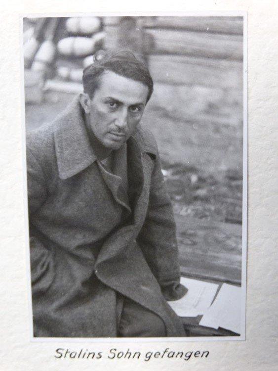 Yakov Jugashvili looks directly at the camera with one eyebrow raised, wearing a long dark military coat.