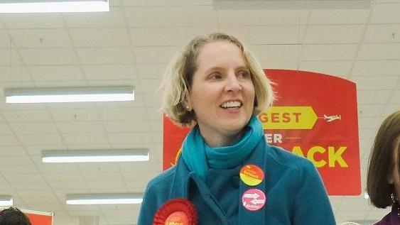 Emma Reyolds wearing a red Labour rosette, campaigning in a supermarket