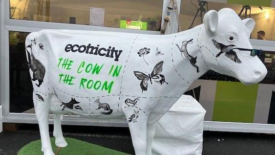 White fibreglass cow with "the cow in the room" Ecotricity written on it