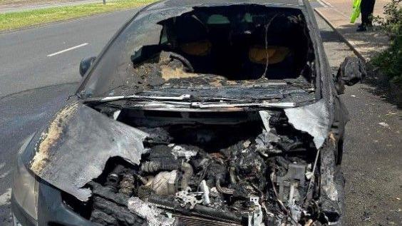 A burnt-out car on the side of a road