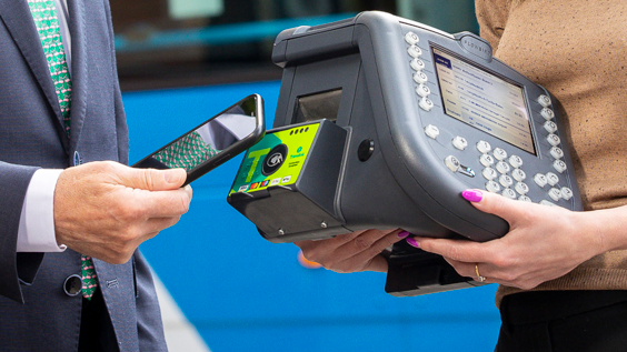 A man taps his phone to a contactless machine 