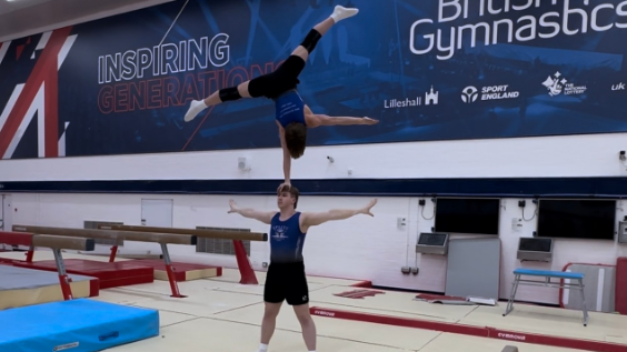 Archie standing in a star shape with Samuel balancing on his head with one hand, also in a star shape