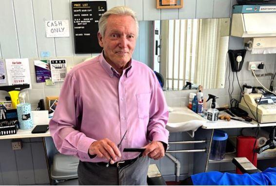 Barber Leon Tooze looking at the camera with a comb and scissors