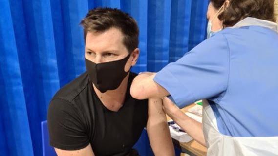 Man in a black mask is given a vaccination