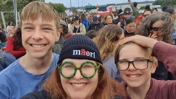 A smiling woman takes a selfie with her two sons