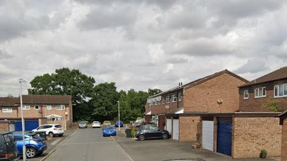 Valley Way, Droitwich. The residential road has several houses with garages and parked cars. At the back of the picture is some trees and some lampposts are also in the photo. 