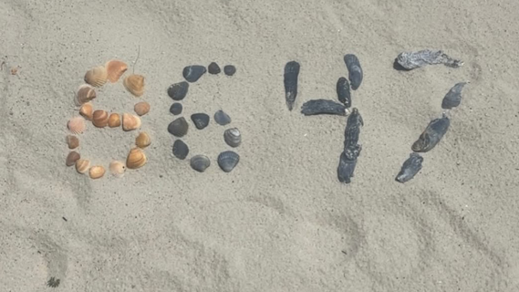 A group of stones in some sand arranged to depict the numbers 8647
