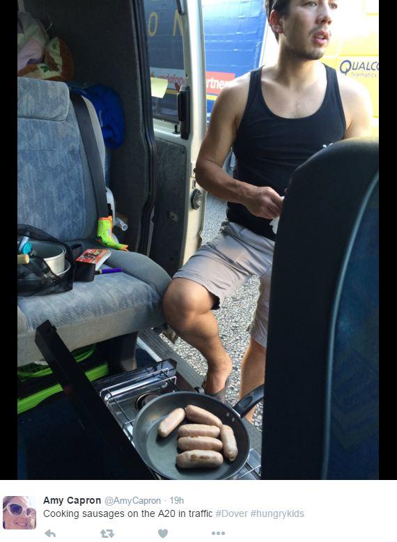 A man cooking sausages in a camper van on a motorway