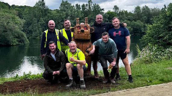 A group photo of the team who installed the wooden sculptures, stood around the Gruffalo statue smiling