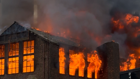 Image shows the inside of Hotspur House, a brick-built Victorian building, raging with fire. Everything inside the frames of the windows burns bright orange.