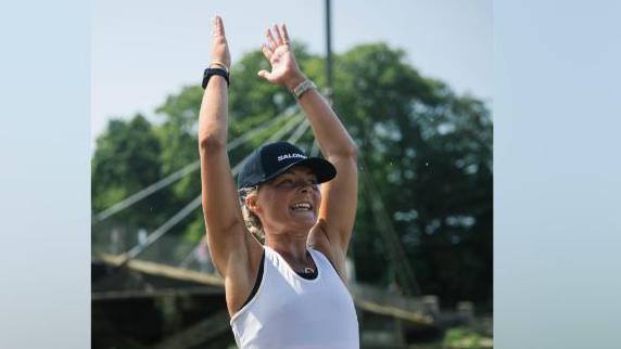 female runner standing with hands above her head