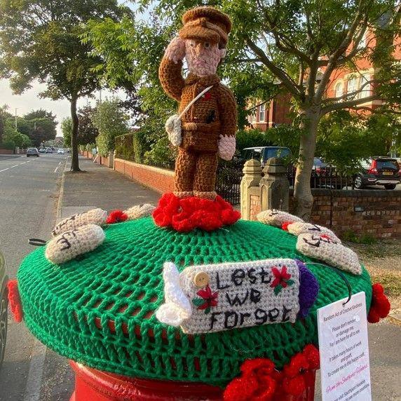 A crochet model of a soldier with the caption 'Lest We Forget' 