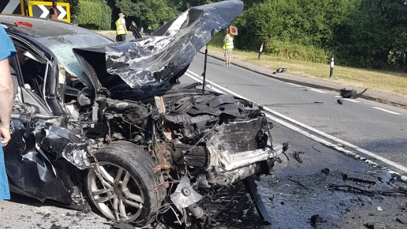 The wreckage of a car in a road with the front end completely crushed