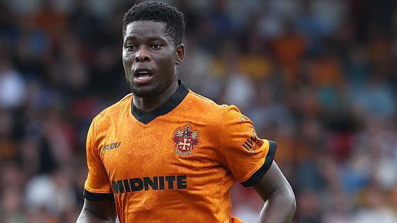 Marshall Munetsi in action for Wolves. He is wearing the club's old gold coloured home shirt.