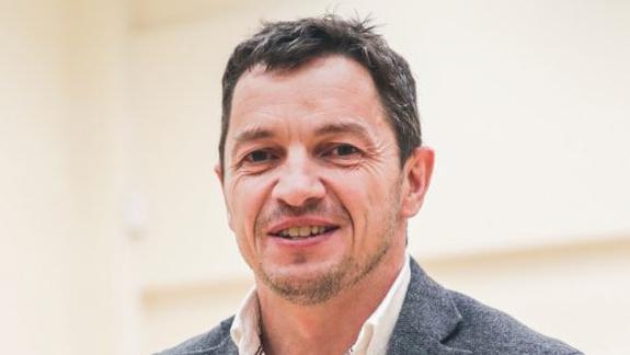 Geraint Evans in white shirt and grey blazer, smiling at the camera