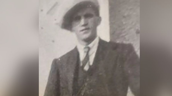 A man in a suit and tie with a cap on - black ad white image