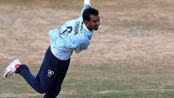 Yuzvendra Chahal at the end of his bowling action, wearing a sky blue top and navy blue trousers for Northants 