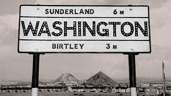 A Washington sign with the colliery behind, coal spoil heaps rising in the background.