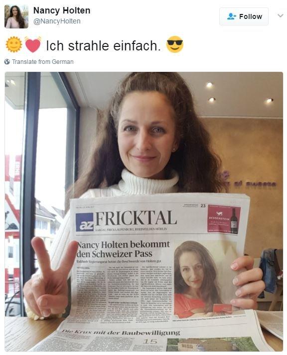 Nancy Holten holding up a newspaper with a headline saying she has her passport