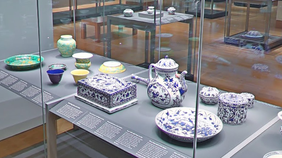 Bowls, a jug, and ceramic boxes in white and blue and green and yellow sit in a display cabinet in the British Museum's Chinese ceramics collection